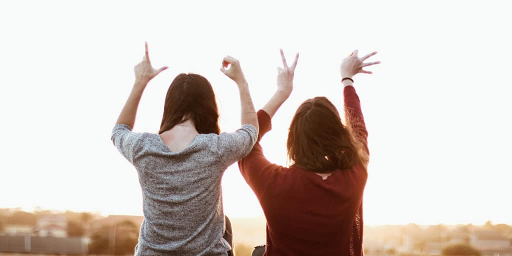 Second Nature. Photo by Sincerely Media on Unsplash. Photo of two people waving their hands in the air.