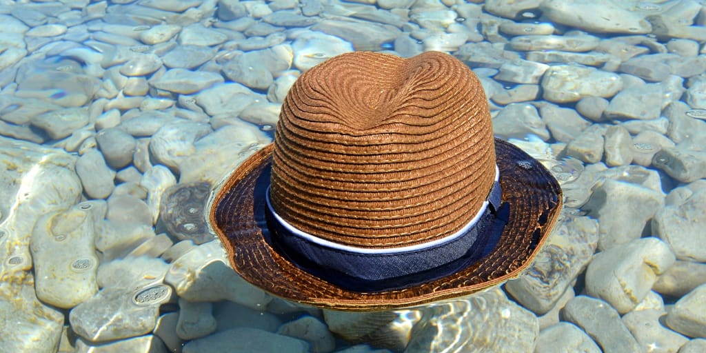 Falling Down. Photo by Michael C on Unsplash. Shows a brown hat hat floating in blue, sunlit water.
