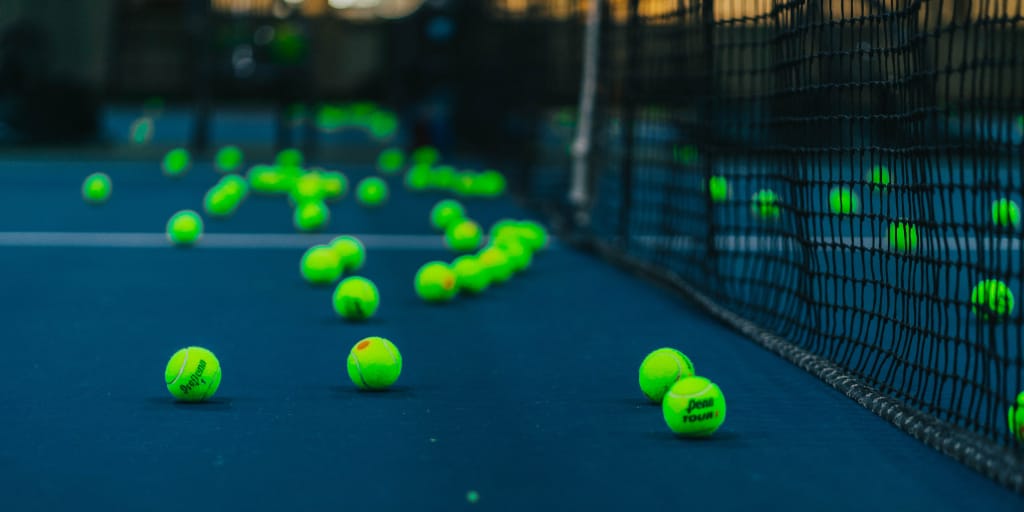 450 Periods_Photo by Hermes Rivera on Unsplash. Shows tennis balls on a court.