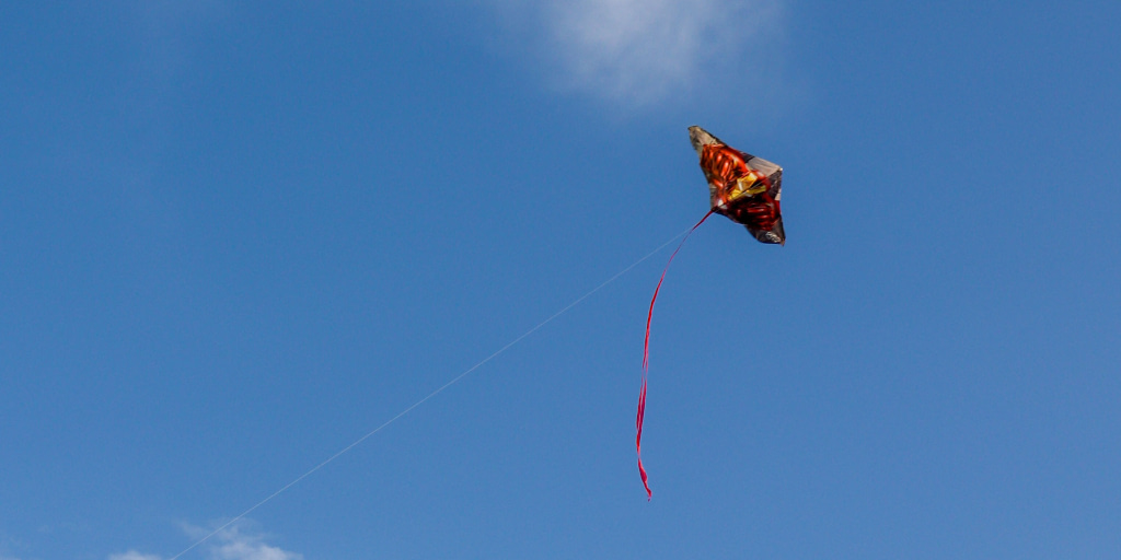 Festival of Kites. Photo by Mitosh on Unsplash. Shows colourful kite flying in a bright blue sky.