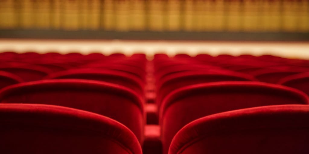 Local Theatre Stages Angel Street. Photo by Paolo Chiabrando on Unsplash. Shows rows of red theatre seats facing a stage.