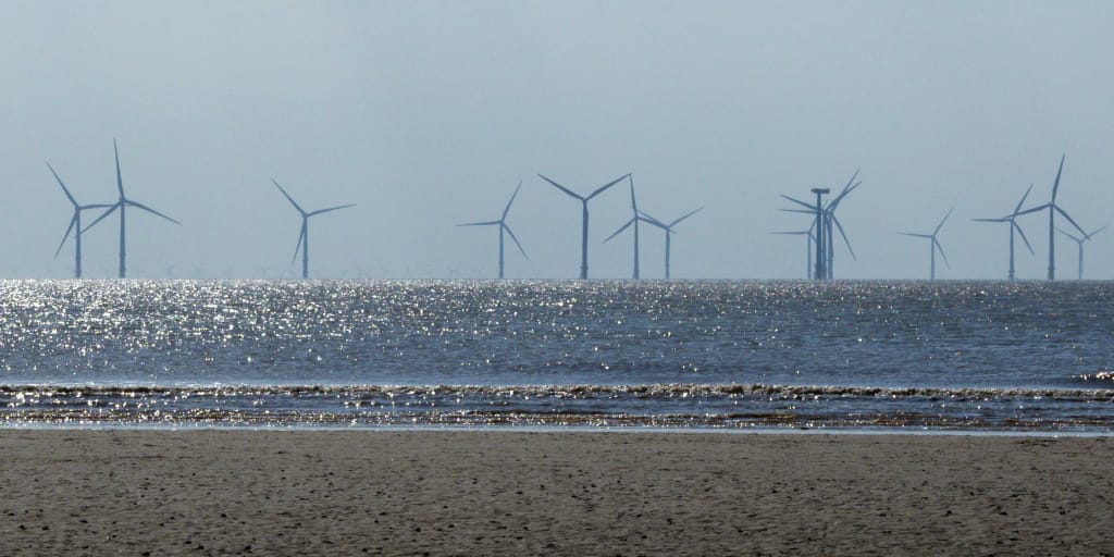 Men Who Stand in Oceans. Photo by Brett Jordan on Unsplash_Shows wind turbines at Crosby Beach, UK