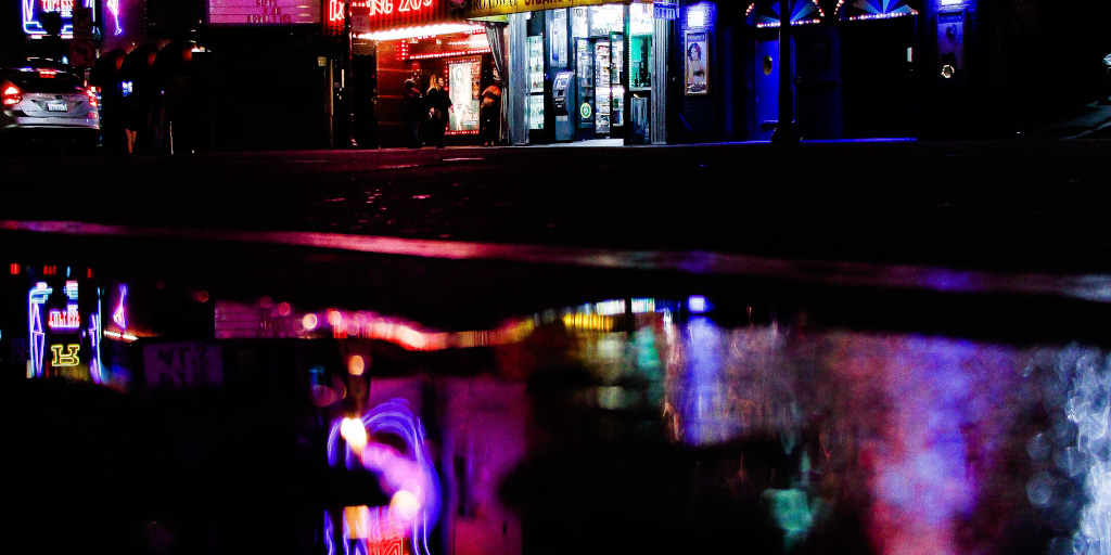 Kaleidoscope_Photo by Justin Bautista on Unsplash. Shows neon lights reflected on wet road at night.