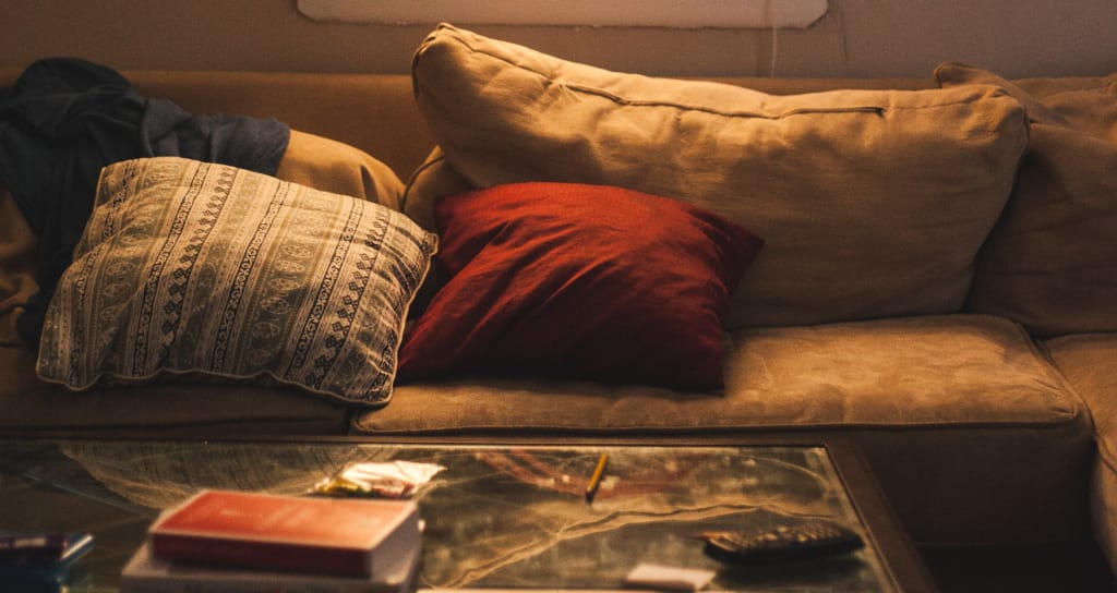 Too Much. Photo by James Fitzgerald on Unsplash. Shows an old couch behind a coffee table.